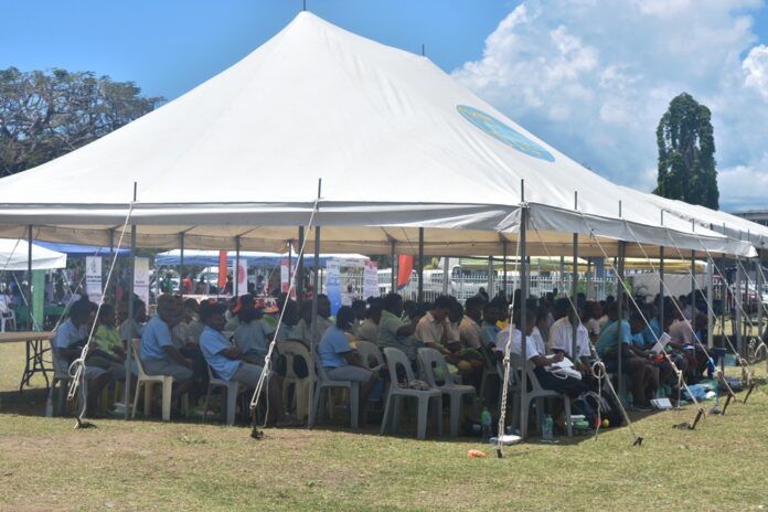 Students sitting under the tent listening to speeches