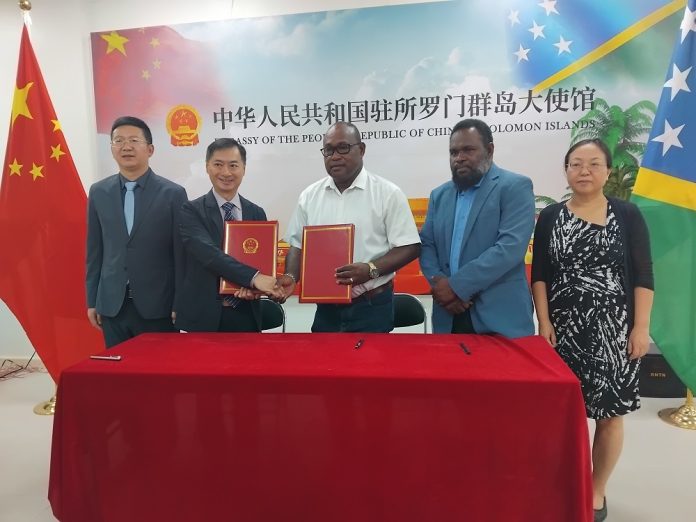 Chinese ambassador Cai Weiming shakes hands with Manasseh Maelanga, MID minister after signing.