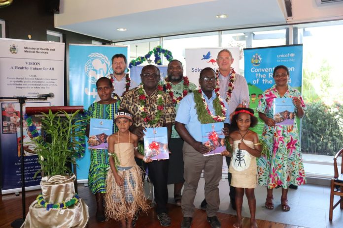 (Front row, left to right) Dr Alependava, PS, MWYCFA and Dr Jilini, Supervising PS, MHMS with officals along with UNICEF and Australia, DFAT representatives display the Implementation Plan document.
