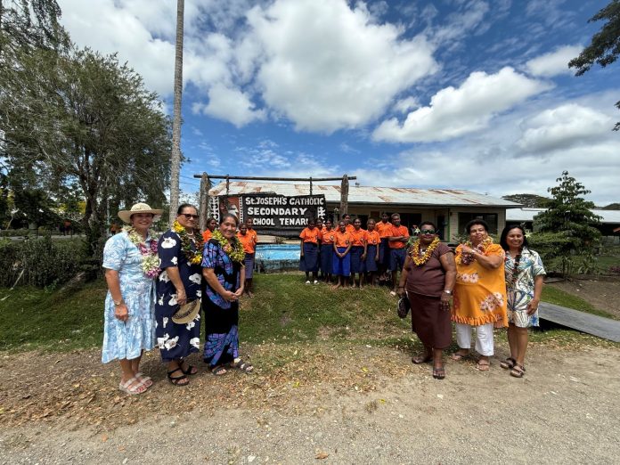 Spouses stand with Tenaru students for a photo.