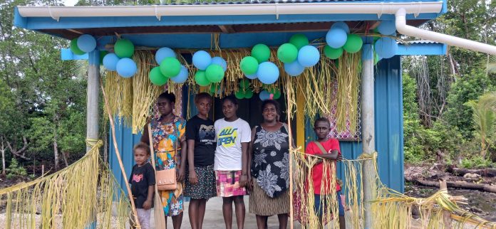 A mother smiles as she join the girls and children for a photo at the Fishery Facility